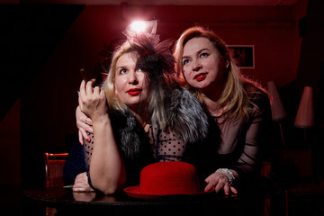 Two fat women in a dark room with red light. Gangsters style