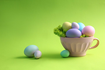 Cup with beautiful Easter eggs on color background