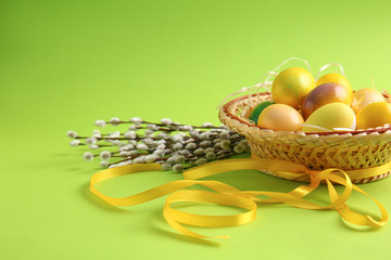 Hat with beautiful Easter eggs and ribbon on color background