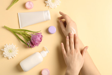 Female hands with natural cream on color background