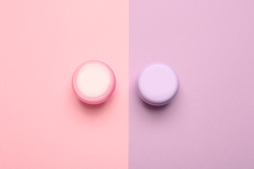 Jars of natural cream on color background