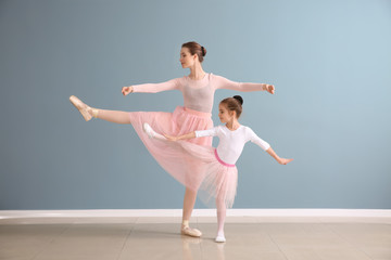 Little ballerina with coach against color wall