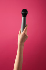 Female hand with microphone on color background