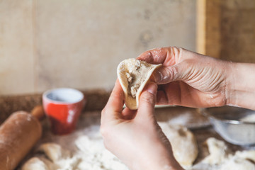 hands of woman make dumpling over granite table