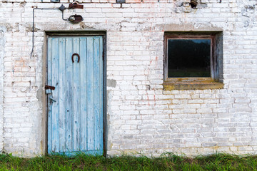 Blue old door and small window of a Soviet-era barn