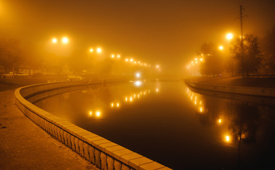 Fototapeta premium Bridge over the river in the city at night in the fog