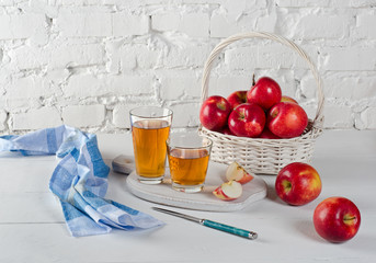 Red apples, juice in glasses, blue napkin and a knife.