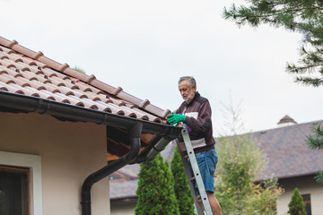 Man repairs tile roof of modern house