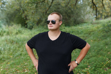 Fototapeta premium portrait of a fat guy in sunglasses on nature