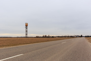 old water tower in a field by the road