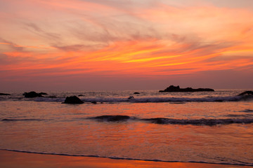 Obraz premium sandy beach shore on the background of rocks in the ocean under a bright sunset sky