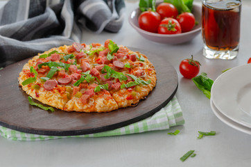 Slices of pizza with greens and salami, cherry tomatoes are on the table.