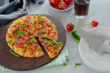 Slices of pizza with greens,sausage and salami, cherry tomatoes are on the table. Top view.