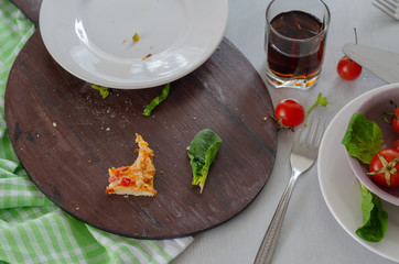 There are remains of pizza,beverage, cheery tomatoes and dirty plate  on the table