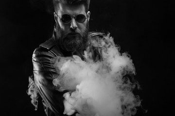 Black and white portrait of serious man wearing a leather jacket in studio photoshoot over black background