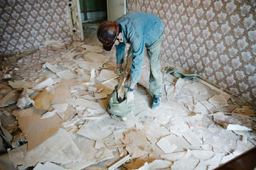 Worker cleans the trash in the apartment in the bag