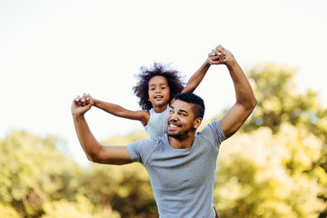 Portrait of young father carrying his daughter on his back