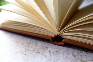 Brown leather vintage notebook blank pages open on bright white and gray concrete color texture table top with empty copy space. Education and studying concept. 