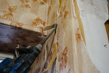 A worker drills a wall using a perforator. Repair in the apartment