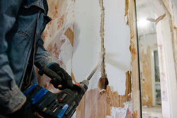A worker drills a wall using a perforator. Repair in the apartment