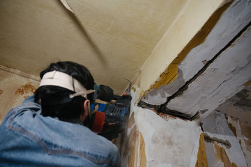A worker drills a wall using a perforator. Repair in the apartment