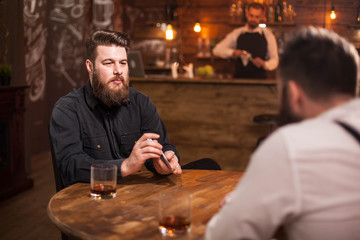 Handsome bearded men playing card in a pub and drinking whiskey