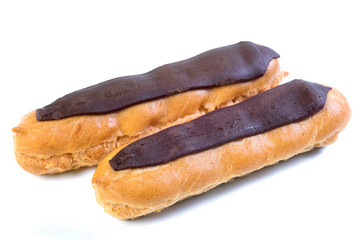 Two eclairs with dark chocolate with custard inside on a white background.