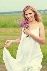 Fototapeta na wymiar outdoor portrait of a middle aged blonde woman. attractive sexy girl in a field with flowers
