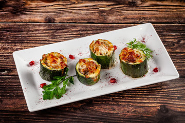 Concept of Georgian cuisine. Stuffed zucchini with minced lamb meat, Suluguni cheese. Serving dishes in a restaurant on a white plate with pomegranate. copy space, background image