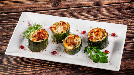 Concept of Georgian cuisine. Stuffed zucchini with minced lamb meat, Suluguni cheese. Serving dishes in a restaurant on a white plate with pomegranate. copy space, background image