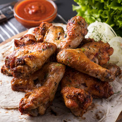 Tasty roasted chicken wings with red sauce and onion. Closeup