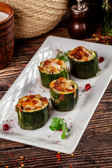 Concept of Georgian cuisine. Stuffed zucchini with minced lamb meat, Suluguni cheese. Serving dishes in a restaurant on a white plate with pomegranate. copy space, background image