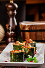 Concept of Georgian cuisine. Stuffed zucchini with minced lamb meat, Suluguni cheese. Serving dishes in a restaurant on a white plate with pomegranate. copy space, background image