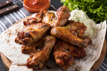 Roasted chicken wings with red sauce. Closeup