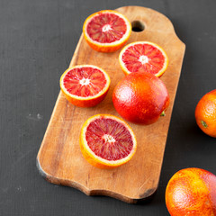 Whole and halved blood oranges on black background, low angle view. Closeup.