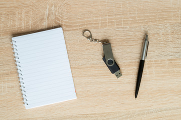 pen and flash drive and Notepad on wooden background