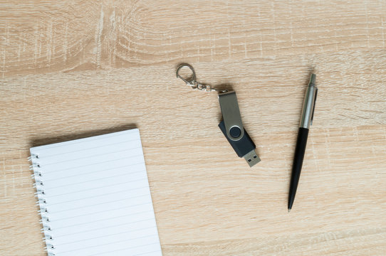 pen and flash drive and Notepad on wooden background
