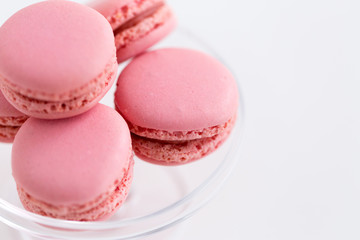 Fototapeta na wymiar sweets, pastry and food concept - close up of pink macarons on glass confectionery stand over white background