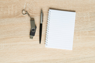 pen and flash drive and Notepad on wooden background