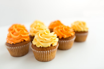 food, pastry and confectionery concept - cupcakes with buttercream frosting over white background