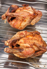 two whole roasted chickens on a rack
