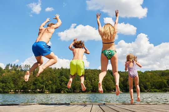 Gl&uuml;ckliche Familie springt in einen See