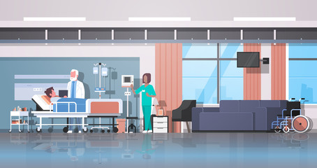 doctor and nurse visiting patient man lying bed with dropper intensive therapy ward healthcare concept hospital room interior modern medical clinic horizontal banner full length