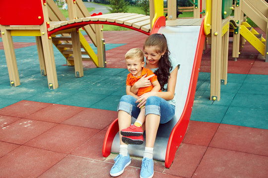 Little Boy On Playground. Playing Child With Mother On A Slide