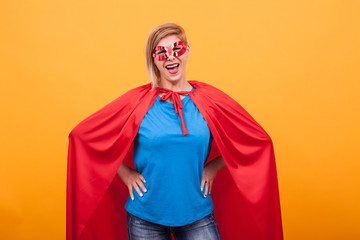 Mother dressed like superheros laughing at the camera over yellow background
