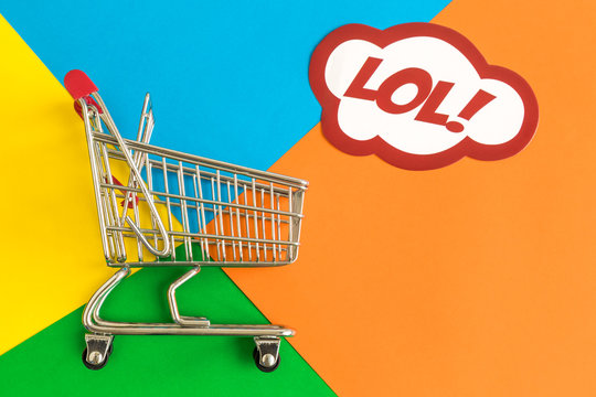 Miniature shopping trolley and label with lol text on multicolored background abstract.