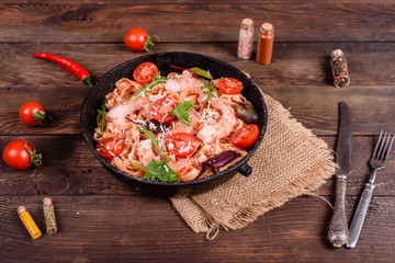 Tasty pasta with shrimp and tomato on a frying pan