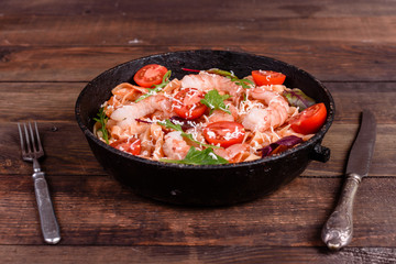 Tasty pasta with shrimp and tomato on a frying pan