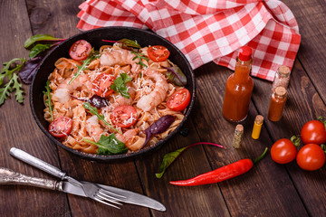 Tasty pasta with shrimp and tomato on a frying pan
