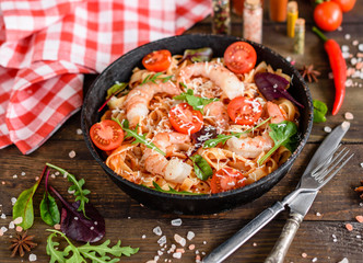 Tasty pasta with shrimp and tomato on a frying pan